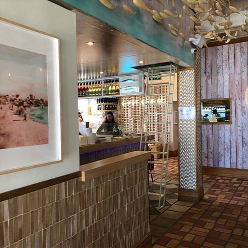 Cozy restaurant interior with wooden accents and decorative ceiling art, creating a warm and inviting atmosphere.