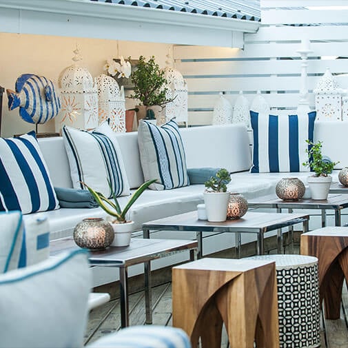 Elegant outdoor lounge with striped cushions and decorative lanterns for a coastal ambiance.