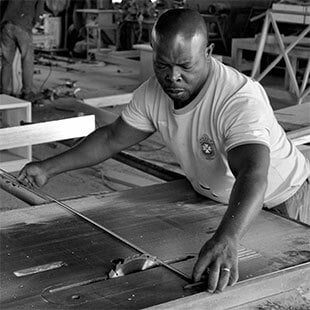 Man measuring timber in woodworking workshop, focused on craftsmanship.