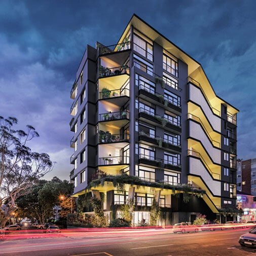 Contemporary multi-storey apartment building with illuminated balconies and modern design.