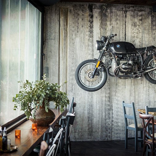Motorcycle mounted on concrete wall in a modern cafe setting in South Africa.