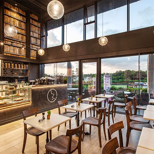 Modern coffee shop interior with large windows, stylish lighting, and cozy seating area for optimal customer experience.