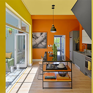 Bright, colourful modern kitchen with orange and yellow walls, open layout and natural light.