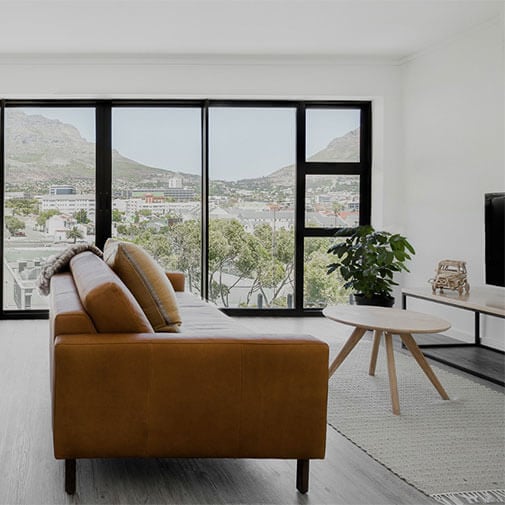 Modern living room with large windows and mountain view, stylish sofa and minimalist decor.