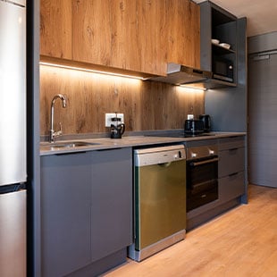 Modern kitchen with grey cabinets and wooden accents, equipped with appliances for contemporary living.