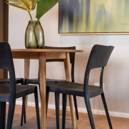 Modern dining room with a wooden table and black chairs, stylish decor and minimalist design.