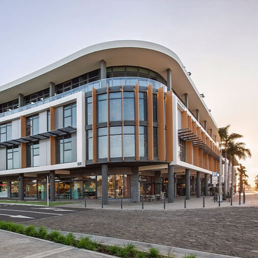 Co-Curate modern multi-storey building with glass facade and wooden accents in an urban setting in South Africa.